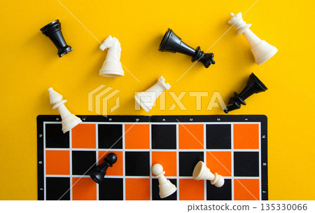Chess pieces falling on orange board against yellow background Chess pieces falling on orange board against yellow background 135330066
