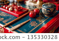 一張擺放在藍紅相間漆桌上的筷子和餐具的照片。 135330328