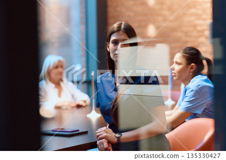 Nurse observes team discussion in modern hospital setting during afternoon hours Nurse observes team discussion in modern hospital setting during afternoon hours 135330427