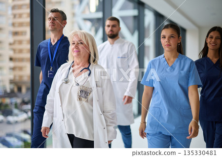 Medical team walks confidently through hospital corridor showcasing unity and dedication to patient care Medical team walks confidently through hospital corridor showcasing unity and dedication to patient care 135330481