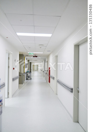 Bright and clean hospital corridor with doors leading to patient rooms and medical areas 135330486