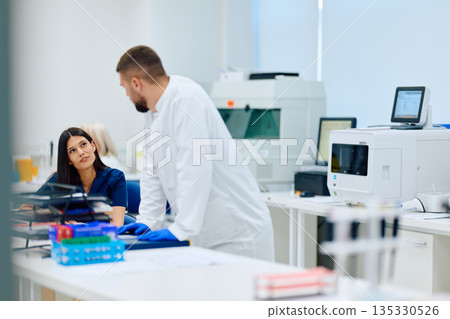 Laboratory team collaborates on scientific research in a modern facility during the daytime Laboratory team collaborates on scientific research in a modern facility during the daytime 135330526