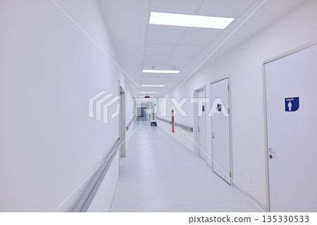 Healthcare facility hallway with clean design and accessible restrooms located on multiple sides 135330533