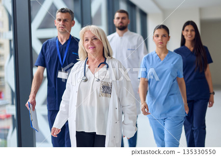 Dedicated healthcare team walking in a modern hospital corridor during the day, focused on patient care and teamwork Dedicated healthcare team walking in a modern hospital corridor during the day, focused on patient care and teamwork 135330550