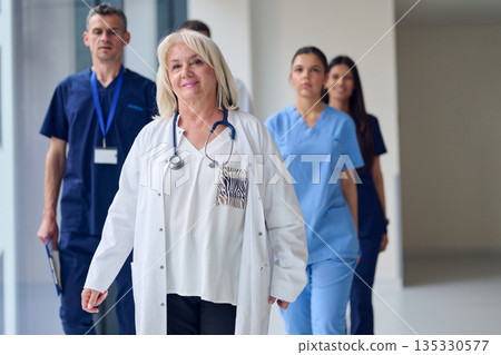 Healthcare team walking down a modern hospital corridor during a busy shift in a well-lit environment 135330577