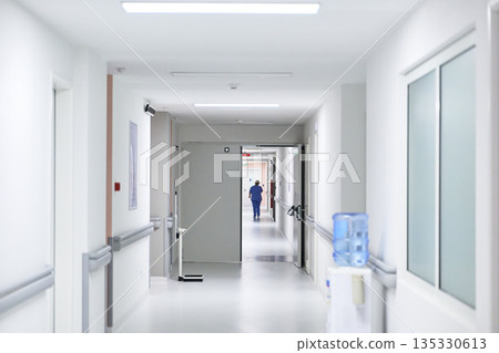 Nurse walking down a hospital corridor during daytime work hours in a healthcare facility 135330613