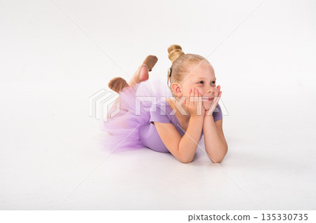 A young dancer with a cochlear implant rests on the floor in a lavender tutu. Inclusive ballet, hearing support, and peaceful childhood expression through imagination and quiet dance moments. A young dancer with a cochlear implant rests on the floor in a lavender tutu. Inclusive ballet, hearing support, and peaceful childhood expression through imagination and quiet dance moments. 135330735