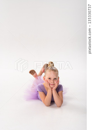 A young ballerina with a cochlear implant lies on the floor resting her face in her hands. Inclusive childhood, hearing technology, and calm imagination through dance and quiet moments. A young ballerina with a cochlear implant lies on the floor resting her face in her hands. Inclusive childhood, hearing technology, and calm imagination through dance and quiet moments. 135330737