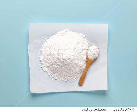 Home cleaning blogs. Pile of powdered detergent with a wooden spoon on kraft paper on a white background. Home cleaning blogs. Pile of powdered detergent with a wooden spoon on kraft paper on a white background. 135330777