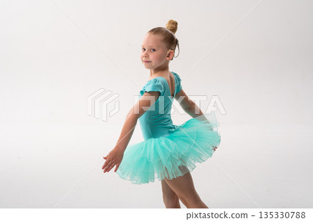 Young ballerina with a cochlear implant turns in a turquoise tutu in the studio. Inclusive ballet, auditory technology, and joyful childhood expression through dance and movement. 135330788