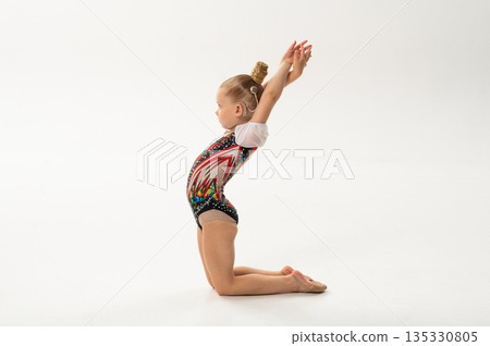 Young gymnast with a cochlear implant performs a graceful backbend in a studio. Copy space. Inclusive sport, hearing technology, rehabilitation, and artistic movement through rhythmic gymnastics and 135330805