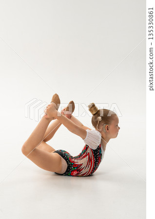 Rhythmic gymnast with cochlear implant stretching on floor in studio. Hearing rehabilitation, body awareness and inclusive childhood flexibility through controlled movement 135330861