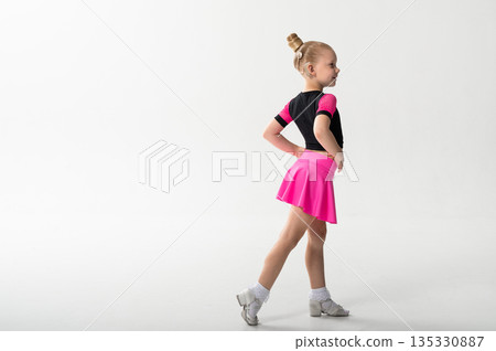 Side view of dancer with cochlear implant in pink skirt in studio. Copy space. Hearing rehabilitation, posture control and inclusive artistic childhood development through ballroom training Side view of dancer with cochlear implant in pink skirt in studio. Copy space. Hearing rehabilitation, posture control and inclusive artistic childhood development through ballroom training 135330887