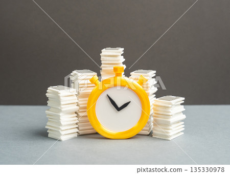 Stacks of papers and a stopwatch. Paperwork and bureaucratic burden on businesses. Reporting deadlines. Administrative overload, time pressure and compliance costs reducing productivity Stacks of papers and a stopwatch. Paperwork and bureaucratic burden on businesses. Reporting deadlines. Administrative overload, time pressure and compliance costs reducing productivity 135330978