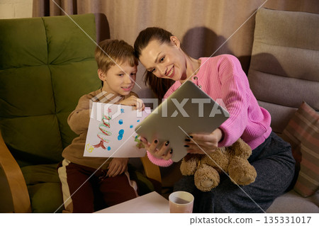 Mother and little boy taking a picture with child drawing on tablet at home. 135331017