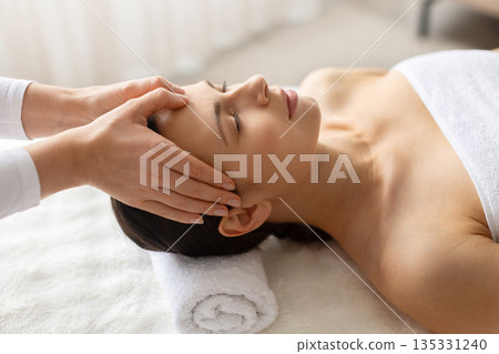 Closeup of young beautiful woman receiving facial massage at spa 135331240