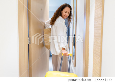 Adult caucasian woman entering hotel room with yellow suitcase, first arrival moment Adult caucasian woman entering hotel room with yellow suitcase, first arrival moment 135331272