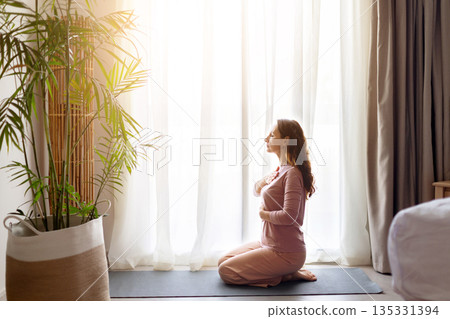 Adult caucasian woman practicing yoga on mat in hotel room near window Adult caucasian woman practicing yoga on mat in hotel room near window 135331394
