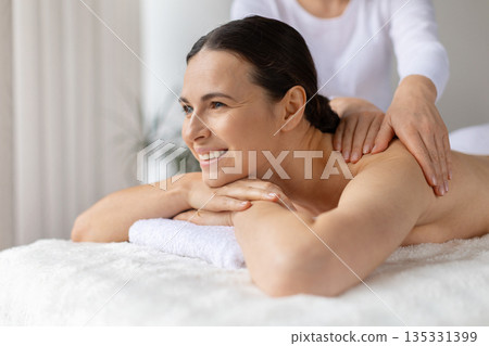 Professional therapist making spa massage to young smiling woman in wellness center Professional therapist making spa massage to young smiling woman in wellness center 135331399