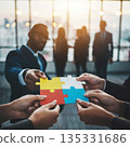 Team members work together to connect puzzle pieces in a meeting room during a late afternoon gathering in the office space 135331686