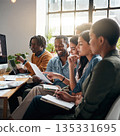 People working together in a group in a bright office space during the day while sharing ideas and discussing plans 135331695