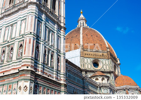 Detailed view of Santa Maria del Fiore cathedral in Florence, showing the iconic red dome and the nearby bell tower, highlighting the rich Renaissance architecture and historic elegance. 135332009
