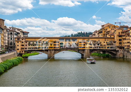 View of Ponte Vecchio in Florence (Ponte Vecchio, Firenze) and nearby buildings along the Arno River on a bright summer day, capturing the historic charm and vibrant riverside scene. View of Ponte Vecchio in Florence (Ponte Vecchio, Firenze) and nearby buildings along the Arno River on a bright summer day, capturing the historic charm and vibrant riverside scene. 135332012