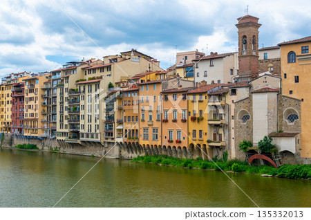 View of Ponte Vecchio in Florence (Ponte Vecchio, Firenze) and nearby buildings along the Arno River on a bright summer day, capturing the historic charm and vibrant riverside scene. 135332013