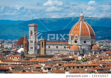 Panoramic view of Florence (Firenze), Italy, showing rooftops, landmarks like Palazzo Vecchio and Santa Maria del Fiore with its red dome, and hills with forests on a sunny summer day. Panoramic view of Florence (Firenze), Italy, showing rooftops, landmarks like Palazzo Vecchio and Santa Maria del Fiore with its red dome, and hills with forests on a sunny summer day. 135332017