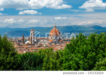 Panoramic view of Florence (Firenze), Italy, showing rooftops, landmarks like Palazzo Vecchio and Santa Maria del Fiore with its red dome, and hills with forests on a sunny summer day. Panoramic view of Florence (Firenze), Italy, showing rooftops, landmarks like Palazzo Vecchio and Santa Maria del Fiore with its red dome, and hills with forests on a sunny summer day. 135332020