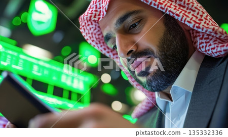 Young Arab man in formal suit reviewing an esg benchmarking report on a tablet at a shared high table 135332336
