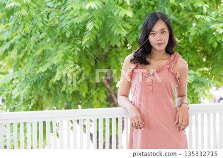 Asian woman in pink dress touching her belly in the garden. Concept of healthy life with nature background Asian woman in pink dress touching her belly in the garden. Concept of healthy life with nature background 135332715