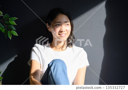 陽光灑在一位女子身上,背景是灰色的。 陽光灑在一位女子身上,背景是灰色的。 135332727