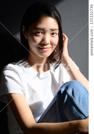 A woman bathed in sunlight against a gray background A woman bathed in sunlight against a gray background 135332736