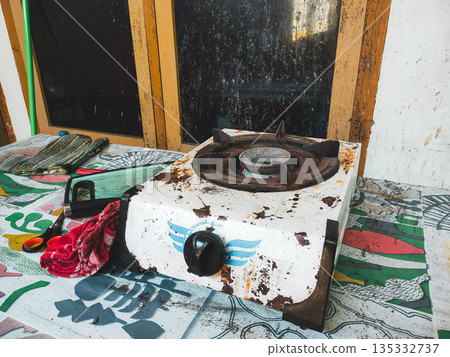 Old Rusty Portable Gas Stove on a Patterned Surface in a Modest Setting Old Rusty Portable Gas Stove on a Patterned Surface in a Modest Setting 135332737