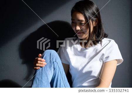A woman bathed in sunlight against a gray background A woman bathed in sunlight against a gray background 135332741