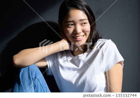 A woman bathed in sunlight against a gray background A woman bathed in sunlight against a gray background 135332744