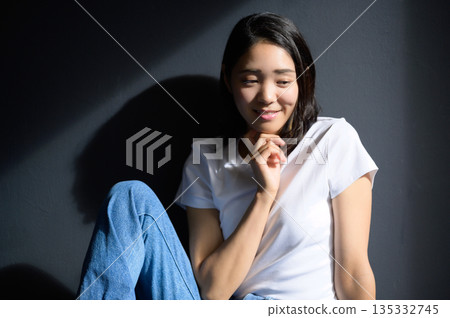 A woman bathed in sunlight against a gray background A woman bathed in sunlight against a gray background 135332745