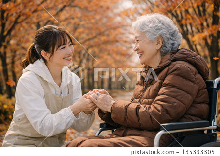 在柔和的秋日陽光下,護理人員和患者手牽手,悠閒地漫步在落葉鋪滿的街道上。 在柔和的秋日陽光下,護理人員和患者手牽手,悠閒地漫步在落葉鋪滿的街道上。 135333305