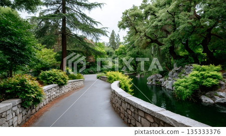 Park pathway winding by a tranquil pond 135333376