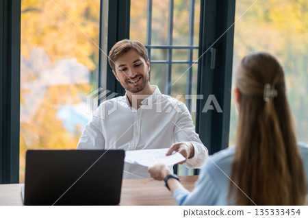 Manager talking to a new hire and looking contented Manager talking to a new hire and looking contented 135333454