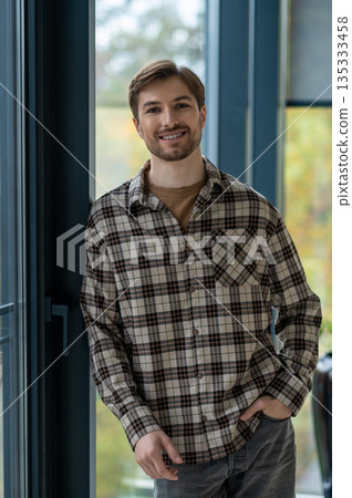 Young man in plaid shirt looking confident and smiling nicely 135333458