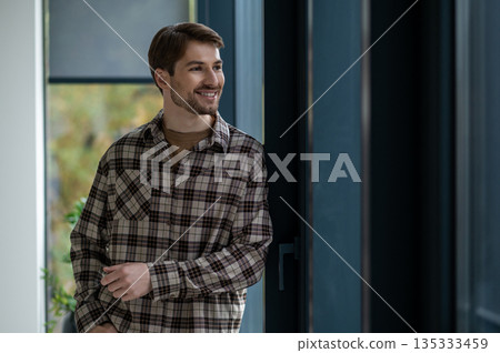 Young man in plaid shirt looking confident and smiling nicely 135333459