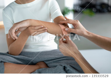 Nurse assisting young girl with skin injury care indoors 135333529