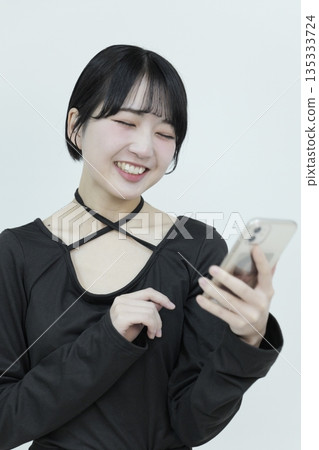 A young woman in black clothes smiling and talking on her smartphone A young woman in black clothes smiling and talking on her smartphone 135333724