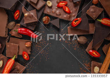 Spicy Chocolate Pieces with Chili and Nuts on Dark Background 135333957