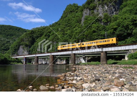 一列由兩節車廂組成的115系列車行駛在白眉線上,穿過綠意盎然的高橋川。 一列由兩節車廂組成的115系列車行駛在白眉線上,穿過綠意盎然的高橋川。 135334104