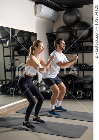 Two young people exercising in the gym in squatting position 135334120