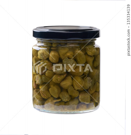 Glass jar with pickled capers isolated on a white background. Glass jar with pickled capers isolated on a white background. 135334139