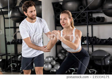 Blonde young woman exercising in the gym with a coach 135334175